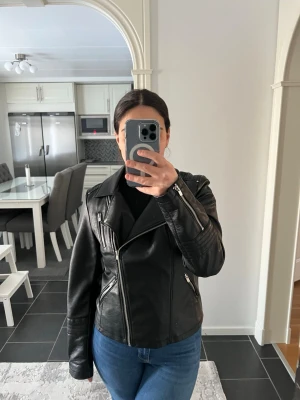 Svart biker skinnjacka med dragkedjor - Säljer en svart skinnjacka i klassisk bikerstil med snedställd dragkedja, breda slag och flera silverfärgade dragkedjor. Jackan har en figurnära passform och coola detaljer som axelklaffar och fickor med dragkedja. Perfekt för en edgy look. Nypris: 549kr. Knappt använd - max en eller två gånger! Pris går att diskuteras!!!