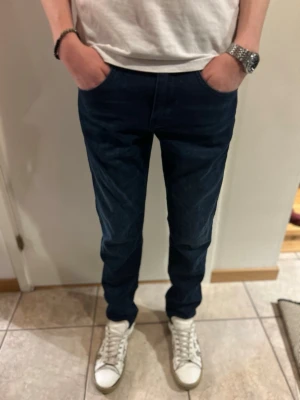 Mörkblå slim fit jeans J.Lindeberg - Snygga mörkblå jeans från J.Lindeberg, modell Jay med mid-rise och slim fit passform. Inköpta för runt 1500 och knappt använda. Materialet är mjukt och stretchigt för extra komfort.