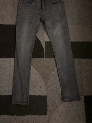 Grå slim fit jeans - Snygga grå jeans i slim fit-modell med klassisk femficksdesign. Jeansen har en diskret tvättad look och raka ben. Perfekta till vardagsstilen och lätta att matcha med olika outfits. Använda ungefär 2 gånger