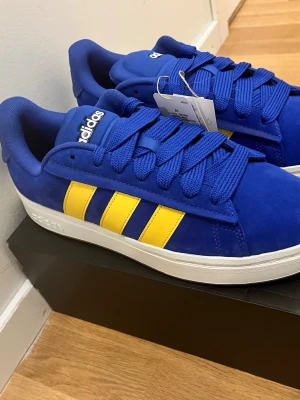 Adidas Grand Court Alpha 00 blå/gul sneakers – stl 44 – nya (nypris 700 kr) - Adidas Grand Court Alpha 00 sneakers i blå/gul färg.  Storlek: 44   Skick: Helt nya, aldrig använda   Med etikett och originalkartong.  Nypris ca 700 kr.  Säljes då storleken inte passar.   Kan skickas eller mötas upp i Stockholm.  #adidas #sneakers #streetwear #blå #44
