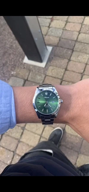 Grön klocka från Doventi  - Stilren klocka från Olevs med grön urtavla och leaf-mönster, silverfärgade index, datumvisning och ett klassiskt metallarmband i silver. Klockan har en rund boett och quartz-urverk som ger en modern och clean look.