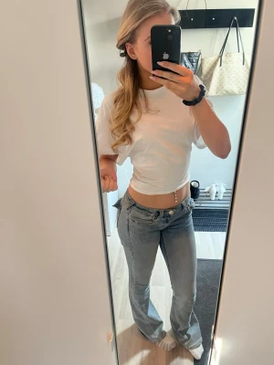 Vit croppad t-shirt med korta ärmar - Säljer en enkel och stilren vit t-shirt med korta ärmar och croppad passform. Perfekt för dig som gillar en avslappnad och trendig look. T-shirten har rund hals och är gjord i mjukt bomullsmaterial.