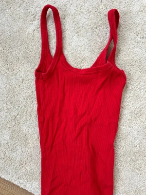 Röd ribbad linnetopp från Weekday - Snygg röd ribbad linnetopp från Weekday med smala axelband och stretchig passform. Perfekt att styla till jeans eller kjol för en enkel och trendig look. Materialet är mjukt och följsamt, vilket gör toppen superbekväm.