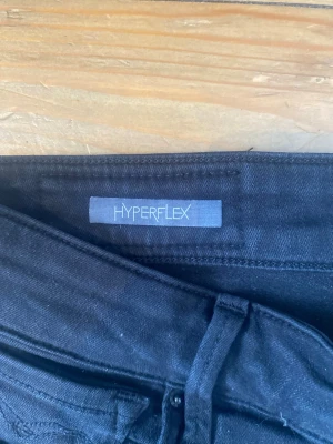 Svarta jeans från Replay - Modell Hyperflex, Snygga svarta jeans från Replay. Jeansen har klassisk femficksdesign, stretchigt material och normal midja. Perfekta för dig som vill ha en tight passform och bekväm känsla hela dagen. storlek 31/32
