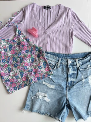 Y2K outfit bundle: cropped cardigan + halterneck + denim shorts + hårklämma - stl S - Y2K inspirerat outfit bundle i lila 💜🌸  Kit med 4 delar: • lila croppad cardigan • blommig halterneck topp • blå denim shorts • rosa hårklämma med rhinestones. Varumärken: Bikbok, H&M, Missguided.  Perfekt somrig Y2K outfit 💖 Alla plagg i fint skick. Kolla gärna in mina andra kit 💌 Fler bilder finns!