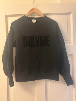 Svart sweatshirt från Dante - Cool svart sweatshirt från Dante med stor D6LVME-text i sammet på bröstet. Tröjan har rund halsringning, långa ärmar och ribbade muddar vid ärmslut och nederkant. Perfekt för en avslappnad streetwear-look. Är i storlek M men sitter mer som en S
