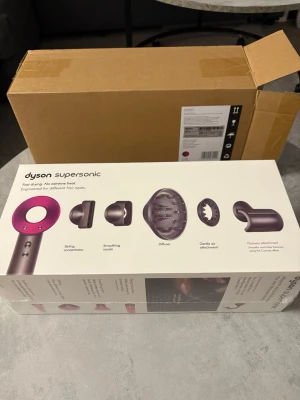 Oöppnad Dyson Supersonic HD08 - Den är oöppnad, Dyson Supersonic hårfön. Designad för snabb torkning utan extrem värme. Hjälper till att skydda naturlig glans. Inkluderar fem stylingtillbehör: koncentrator, utslätande munstycke, diffuser, skonsamt lufttillbehör och flyaway-tillbehör.