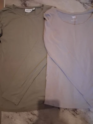 Två långärmade baströjor XS - Säljer två långärmade baströjor i storlek XS. Ena är olivgrön från Kappahl och den andra är beige från 157. Båda har rund halsringning och är perfekta som enkla vardagstoppar. Materialet känns mjukt och stretchigt, troligen bomull eller bomullsblandning.