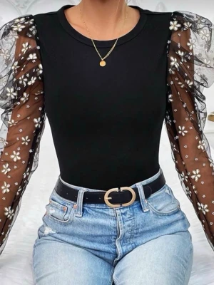 Svart topp med sopuffärmar och blommor - ,Svart topp med transparenta puffärmar i mesh dekorerade med vita blommor. Kroppen är åtsittande och enfärgad medan ärmarna har volangdetaljer och blommigt mönster. Perfekt för dig som vill sticka ut lite extra.