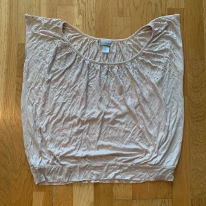 Ljusrosa topp med stenar från H&M - Snygg ljusrosa topp från H&M med små stenar vid halsringningen. Toppen har en lös passform, bred urringning och är ärmlös. Perfekt att styla med jeans eller kjol för en trendig look.