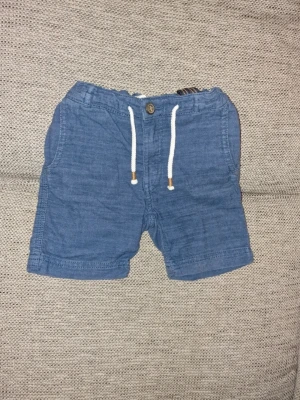 Blå shorts med snörning - De är något blekta i färgen efter att ha tvättats och det finns någon tråd som letat sig upp från sin plats (se bilder). Stl 98 