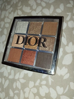Dior ögonskuggspalett i varma toner - Snygg ögonskuggspalett från Dior med nio nyanser i varma och neutrala färger. Paletten innehåller både matta och skimrande skuggor i beige, brunt, guld, koppar och champagne. Perfekt för att skapa olika looks. Lyxig förpackning med Dior-logga. Nästan helt ny bara testad, fick den som present men jag använder inte smink