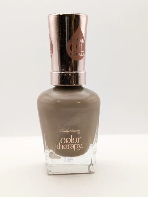 Sally Hansen Color Therapy Chai Hopes 80% kvar - Snyggt nagellack från Sally Hansen Color Therapy i nyansen Chai. Färgen är en mjuk, beige-brun ton med en hint av grått och har en glansig finish. Innehåller arganolja för extra vård. Kommer i en stilren glasflaska med roséguldfärgat lock.