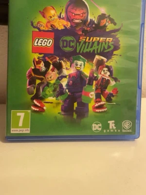LEGO DC Super-Villains PS4 spel - Säljer ett PlayStation 4-spel: LEGO DC Super-Villains. Spelet har ett färgstarkt omslag med DC-skurkar i LEGO-format och kommer i en blå plastbox. Skivan har coola grafiska detaljer och spelet är PEGI 7. Perfekt för dig som gillar action och superhjältar.