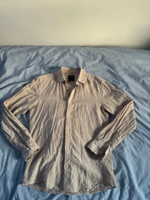 Beige linneskjorta från Only&Sons - Säljer en stilren beige skjorta från Only&Sons i mjukt linne. Skjortan har klassisk krage, långa ärmar och knappar framtill. Perfekt för en avslappnad men ändå snygg look. Passar till både jeans och chinos.