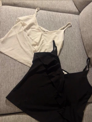 vit och svart topp - Två stilrena toppar i svart och vitt med smala axelband och dekorativ volang framtill. Använd fåtal gånger båda är i XS! Pefekt till sommaren!💕