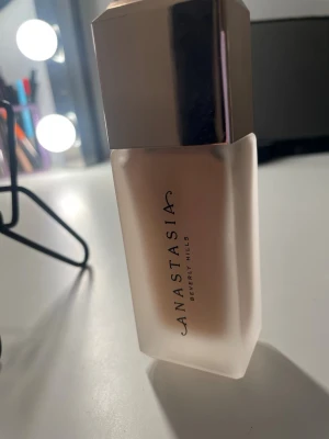 Foundation från Anastasia 2N - Foundation i glasflaska med pump från Anastasia Beverly Hills. Färgen är 2N och flaskan har en elegant, fyrkantig form med metalliskt lock. Perfekt för en jämn och naturlig bas. Pumpen gör det enkelt att dosera rätt mängd produkt. Fulltäckande och blurrande formula