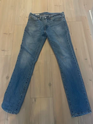 Levi's raka blå jeans - Klassiska blå jeans från Levi's med rak passform och fem fickor. Jeansen har en tidlös tvätt och är tillverkade i slitstark denim. Perfekta för dig som gillar en enkel och clean look. Levi's patch bak i midjan och röd etikett på bakfickan.