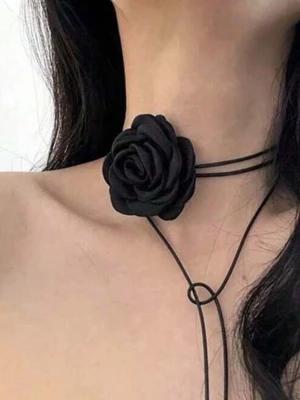 Svart  halsband Necklace choker med rosdetalj - Trendig svart choker med en stor tygros i mitten. Halsbandet har tunna band som kan knytas på olika sätt för en personlig stil. Perfekt accessoar för att ge din outfit en edgy och romantisk touch. Materialet är mjukt tyg och bandet är smalt och flexibelt.