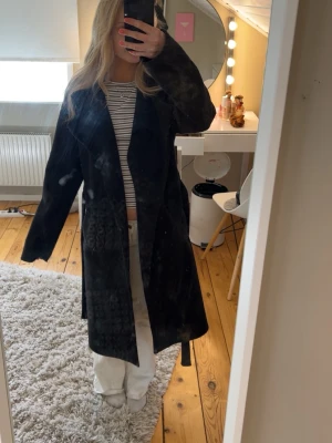 Svart lång kappa - Stilren svart lång kappa med skärp i midjan och rak passform. 