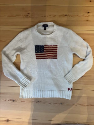 USA sweater/tröja stickad polo Ralph lauren - Polo Ralph lauren tröja som är stickad med ett motiv av ”USA” flaggan🙌 Tröjan är i princip nyskick🎖️ köpt på kidsbrandstore för 2499 kr i januari 2026 använd ett fåtal gånger👀 modellen är längd:179 vikt:67,5 kg🙌🔥 har du några frågor tveka inte att ställa dom🔥 pris inte hugget i sten🪨🪏💸