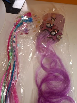 Färgglada hårclips med pärlor och figurer - Två håraccessoarer: ett set med flätade hårclips i rosa, blått och grönt med pärlor, samt ett lila hårclip med glittriga rosetter och söta figurer. Perfekt för att ge håret en lekfull och färgstark touch.