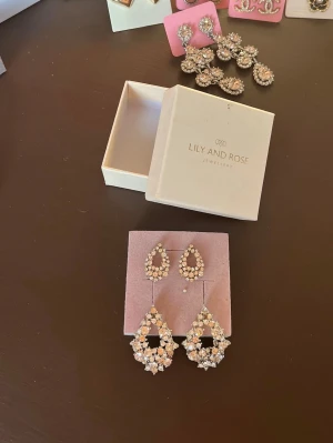 Lily and Rose Miss Alice  - Säljer två par från Lily and Rose. De är modellen Miss Alice nyp 649:- samt Miss Alice Petit nyp 349:- båda är i använt skick men de har mer att ge för den som vill köpa snygga örhängen för ett billigt pris. Jag älskar själv denna modellen och har använt dem mkt men fick nya när jag fyllde år så säljer dessa vidare nu. De saknas några Swarovski kristaller men de syns inte när den används. Glittrar otroligt mycke och fint när de sitter på. Färgen är Crystal- Vitage Rose - Silk pris kan diskuteras