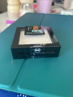 Maybelline Fit Me Matte + Poreless puder - Transparant kompaktpuder från Maybelline Fit Me Matte + Poreless i färgen 090 Translucent. Kommer i en svart fyrkantig dosa med genomskinligt lock. Perfekt för att matta ner huden och ge en jämn finish.