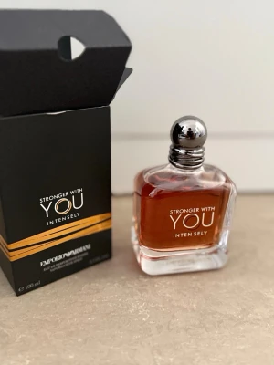 Stronger With You Intensely parfym - Stronger With You Intensely från Emporio Armani är en parfym i en elegant, fyrkantig glasflaska med silverfärgad rund kork. Doften har en djup bärnstensfärg och flaskan rymmer 100 ml. Har bara sprayat den fyra gånger.