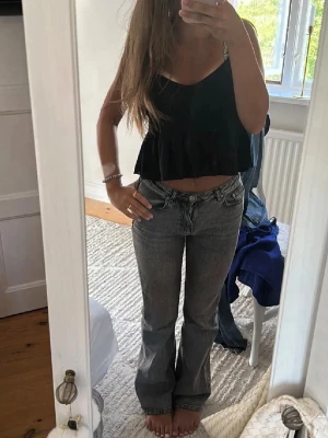Grå bootcut jeans med tvättad look - Säljer ett par grå bootcut jeans med snygg tvättad finish och klassisk femficksmodell. Jeansen har normal midja och utsvängda ben, perfekta till en avslappnad stil. Materialet är denim i bomull. Passar dig som gillar en trendig och bekväm look.