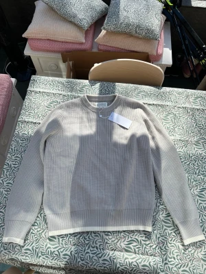 Beige stickad tröja Maison Margiela - 185, 93KG, L-XLSäljer en beige stickad tröja från Maison Margiela. Tröjan har rund halsringning, ribbade muddar och är tillverkad i Italien. Materialet är mjukt och har en diskret struktur som ger en clean look.