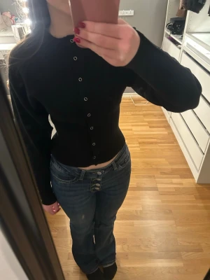 Svart cardigan  - Svart cardigan från Gina Tricot med knappar fram och längst ner vid ärmen. Figursydd passform. Använd fåtal gånger