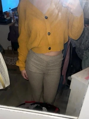 Gul cropped kofta med stora knappar - Säljer en gul, ribbstickad kofta från Lager 157 med stora svarta knappar framtill. Koftan är croppad , har v-ringning och långa ärmar med breda muddar. Perfekt för dig som gillar en avslappnad och trendig stil.