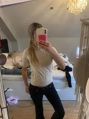 Beige stickad kortärmad topp - Säljer en beige stickad topp med korta ärmar och hög hals. Toppen har en slim passform och är tillverkad i ett mjukt material som sitter snyggt på kroppen. Perfekt att matcha med jeans eller kjol för en clean look. Använd en gång 