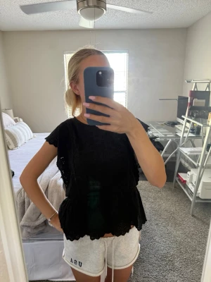 Svart blus - Säljer en svart blus med broderade hålmönster och volangkant nedtill. Helt i nyskick!! Storlek 164 från barnavdelningen, men sitter som en XS.😊