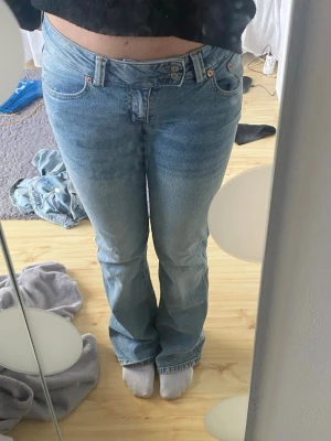 Ljusblå bootcut jeans med brodyr - Säljer ett par ljusblå bootcut jeans med snygg broderad detalj på bakfickan. Jeansen har klassisk femficksmodell, normalhög midja och är tillverkade i denim. 