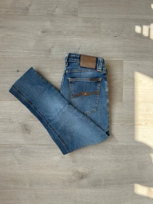 Blåa Skinny Sam Nudie Jeans W26 L32 - Fina Nudie Jeans i blå färg. Jeansen är i mycket bra skick och sparsamt använda. |  Äkta som allt annat jag säljer! ✅|  Storlek: W26 L32 | Skick: Mycket Bra Skick - BLIVIT LAGADE, SE SISTA 2 BILDER | Färg: Blå | Märke: Nudie | Modell: Jeans |  Hör gärna av dig vid frågor så svarar jag så fort jag kan! 😁   (SKU - 9)