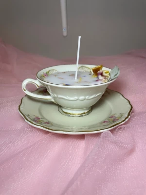 Doftljus i vaniljdoft i en tekopp med fat i blommig design  - Det här ljuset är gjort av återanvändbara material. Tekoppen är köpt secondhand och stearinet är från kyrkor som tänkte slänga det. Det här ljuset har en svag doft utav vanilj, så känsliga även kan använda det. Det här ljuset har även torkade blommor på som dekoration. 