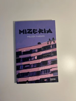 Mizeria av Melody Farshin - Ungdomsroman med lila och rosa omslag, skriven av Melody Farshin. Boken handlar om tvillingarna Aicha och Ali och deras liv i förorten. Omslaget har en illustration av ett höghus och två personer på taket. Perfekt för dig som gillar samtida och realistiska berättelser.