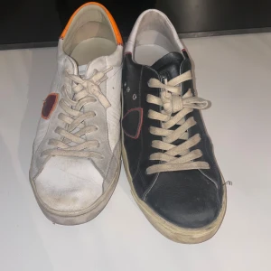 Svart och vit sneakers med färgdetaljer - Unika sneakers i svart och vit med kontrasterande färgdetaljer. Det ena paret är svart med vita snören och de andra är vit med orange och röda detaljer. Skorna har en klassisk snörning och en bekväm sula.   1000kr styck/ rabatt om man köper båda, kan gå ner i pris vid snabb affär