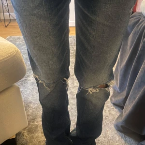 Blå sthl stil jeans från hollister  - Säljer ett par blå jeans med slitningar på knäna. De är straight i modellen och är väldigt trendiga.
