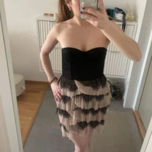 Axelbandslös klänning med spetsdetaljer från hm - Snygg axelbandslös klänning i svart och beige med spetsdetaljer. Klänningen är från hm och är perfekt för festliga kvällar!