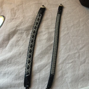 Svarta armband med flätad design - Två svarta armband med en elegant flätad design i silverfärgad tråd. Armbanden har en stilren och tidlös look, perfekt för att komplettera olika outfits. 50kr för båda!