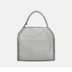 Grå Stella McCartney väska - Snygg grå axelväska från Stella McCartney med kedjedetaljer. Nypris 12.000:-  Har blivit lite använd men inga tecken på det och är nästintill nyskick🌸 suuuper fin och verkligen en fin detalj till alla outfits, perfekt till våren, min favoritväska men har två likadana