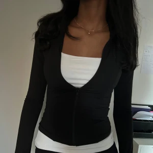 Svart långärmad tröja med dragkedja - Snygg svart långärmad tröja med dragkedja framtill. Perfekt för lager-på-lager och passar till många olika stilar. Enkel och stilren design. Använt fåtal gånger.