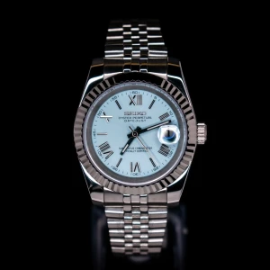 Seiko Mod  - Elegant klocka från Seiko med en ljusblå urtavla och romerska siffror. Den har en silverfärgad boett och armband i rostfritt stål. Klockan har en datumvisare med förstoringsglas och en räfflad bezel som ger en klassisk look. Klockan är i extremt högt kvalite. Materialet är rostfritt stål och rörelsen är 100% japansk. Klockan är testad för vattentäthet, och urtavlan är äkta safirglas. Finner du inte det klocka du söker bland våra katalog hör av dig i DM så bygger vi din drömklocka. 