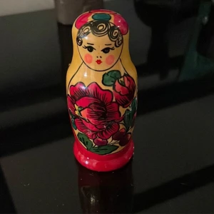 Traditionell rysk matryoshka-docka - Charmig handmålad matryoshka-docka i trä med en  mindre dockor inuti. Den har en färgglad design med blommotiv i rött, gult och grönt. Perfekt som dekorativt inslag eller samlarobjekt.storlek på stora är 9,05cm och lilla är 5,05cm .kan möta er i Stockholm i T-Centralen utanför Åhléns 