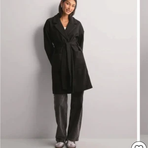 Svart tunnare kappa  - svart kappa i storlek XS från Pieces med knytbälte i midjan. Köpt från Nelly. Aldrig använd. Lite tunnare kappa, perfekt nu till våren. Köparen står för frakten 🩷