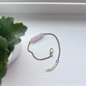 Armband med rosa marmorerad sten - Elegant armband med en ljusrosa sten och en tunn kedja i guldfärg. Armbandet har en justerbar kedja med klolås för enkel användning. Perfekt för att ge en subtil färgklick till din outfit. Jag lägger armbandet i plastfickan som finns på sista bilden, så det inte utsätts för skada vid leverans.