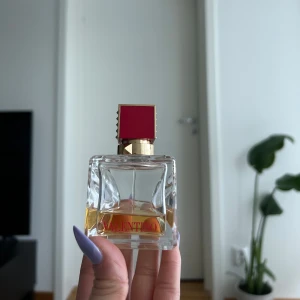 Valentino parfym  - Elegant parfym från Valentino i en fyrkantig glasflaska med en distinkt röd och guldig kork. Flaskan har en klar design som visar den gyllene vätskan inuti. Perfekt för den som söker en lyxig doftupplevelse. Se mängd kvar! Nypris 1000kr